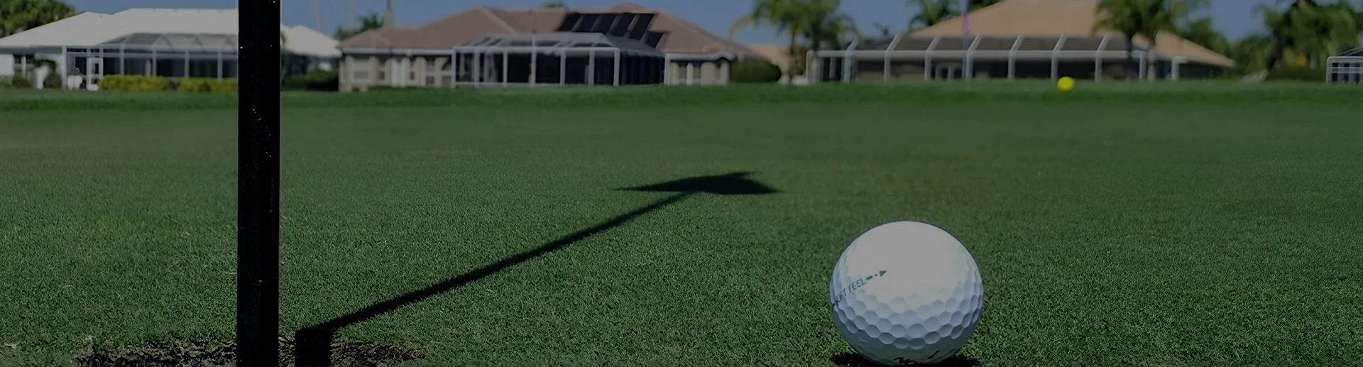 A golf ball is on the grass near a house.