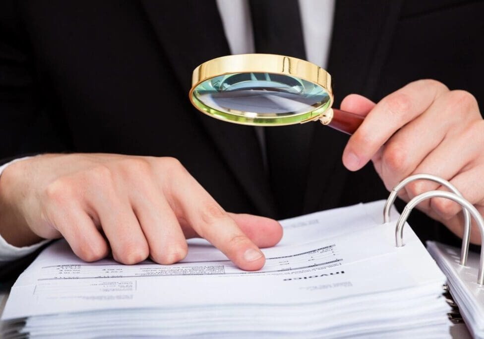qtq80-1FJGII Person examining documents with a magnifying glass.