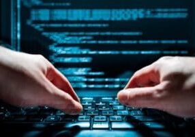 Hands typing on a keyboard with code.